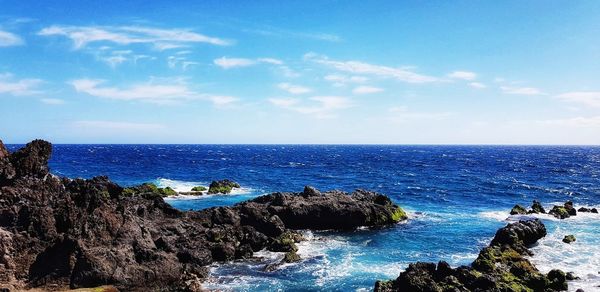 Scenic view of rocks in sea against sky