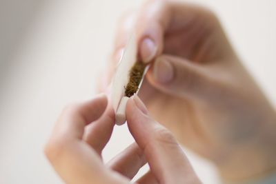 Close-up of cropped hands making marijuana joint