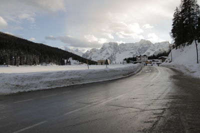 Road by snowcapped mountains against sky