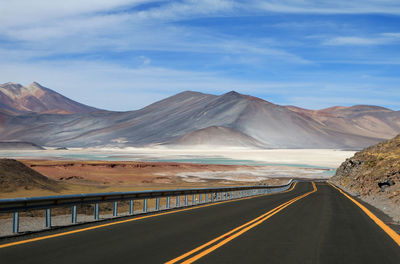 Road leading towards mountains against sky