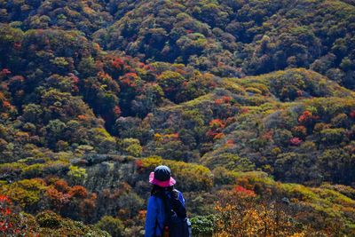 Woman standing by trees in forest during autumn