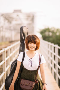 Portrait of smiling woman standing against railing