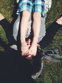 Low section of son on father relaxing over grassy field