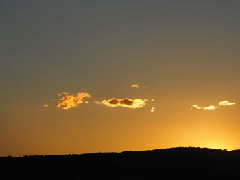 Silhouette landscape against dramatic sky during sunset