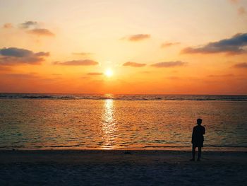 Silhouette man standing at beach during sunset