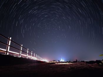 Low angle view of illuminated light trails against sky at night