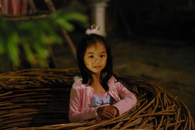 Portrait of cute girl standing by wicker nest