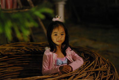 Portrait of cute girl standing by wicker nest