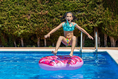 Lttle girl jumping on a rubber ring into a pool