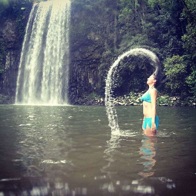 water, motion, lifestyles, splashing, waterfront, leisure activity, full length, waterfall, standing, fountain, flowing water, person, spraying, enjoyment, tree, young adult, nature, elementary age