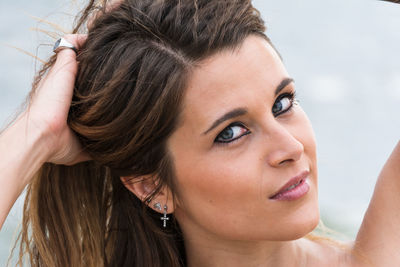 Close-up portrait of woman with hands in hair