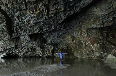 Rear view of young boy standing on rock in cave