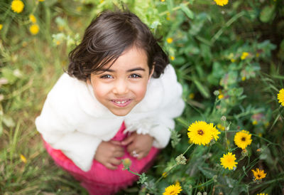 Portrait of smiling girl with yellow flower in field