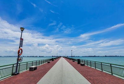 Empty footpath by sea against sky