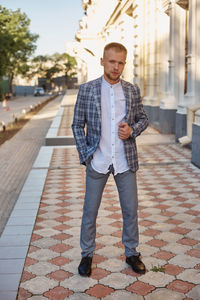 Portrait of young man standing on footpath