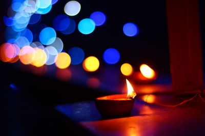 Close-up of illuminated diya on retaining wall at night