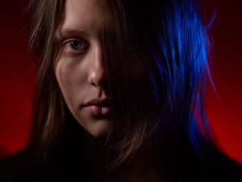 Close-up portrait of beautiful young woman over red background