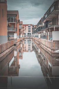 Reflection of buildings in canal against sky