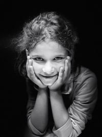 Portrait of smiling girl against black background