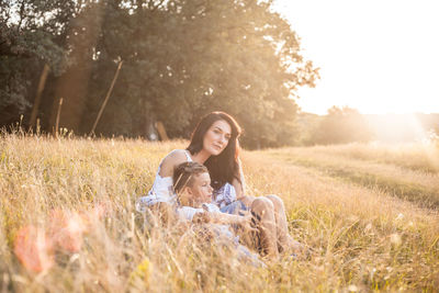Mother and son relaxing on field in sunny day