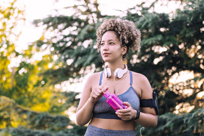 Portrait of beautiful woman standing against tree