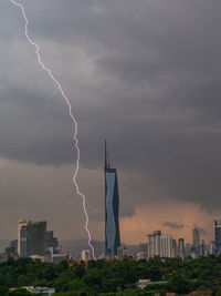 Lightning strike on buildings in city against sky during stormy day