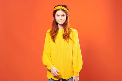 Portrait of woman standing against yellow background