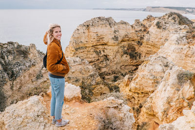 Portrait of smiling young woman standing on cliff