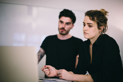 Business people discussing over laptop at desk in creative office