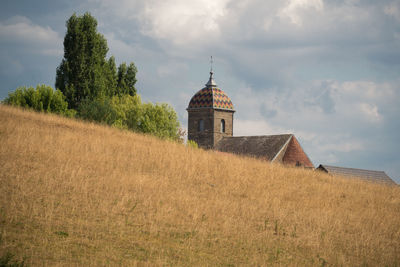 Building on field against cloudy sky