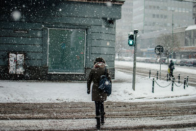 Rear view of woman crossing street during winter