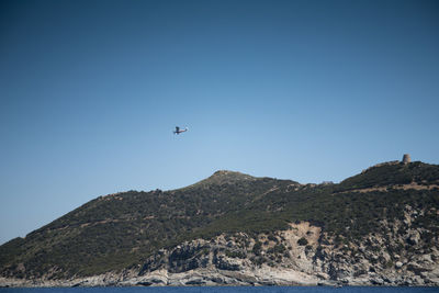 Low angle view of airplane flying against clear blue sky