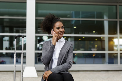 Close-up of businesswoman talking on phone while sitting outdoors