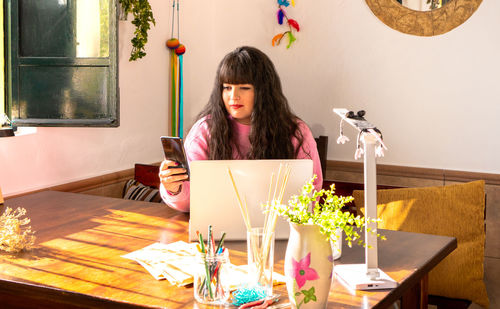 Portrait of woman using mobile phone on table