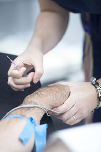 Close-up of female doctor injecting iv drip in patient arm