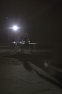 Men playing table tennis at illuminated field