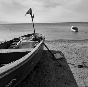 Fishing boat moored on beach against sky