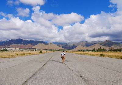 Man walking towards the horizon on an abandoned airfield in kyrgyzstan 
