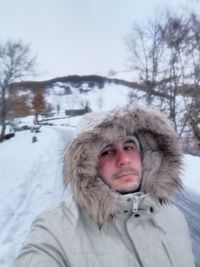 Portrait of man in snow against trees during winter