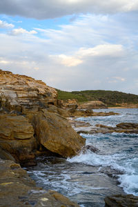 Rock formation on beach against sky