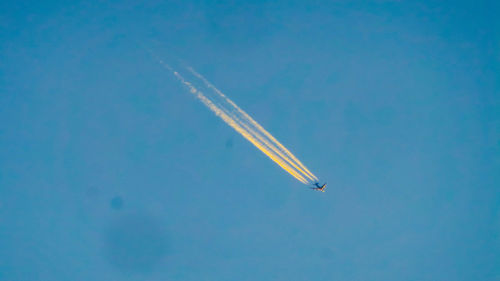 Low angle view of airplane flying against clear blue sky