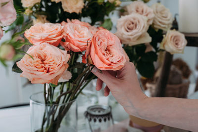 Closeup of hands of young woman florist creating bouquet of pink roses