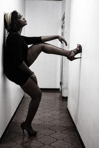 Side view of woman standing against wall at home