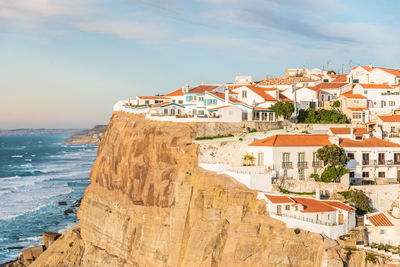 Buildings by sea against sky