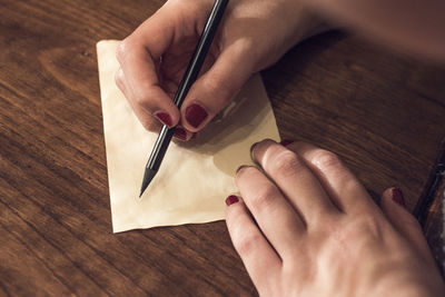Close-up of woman writing on paper at table