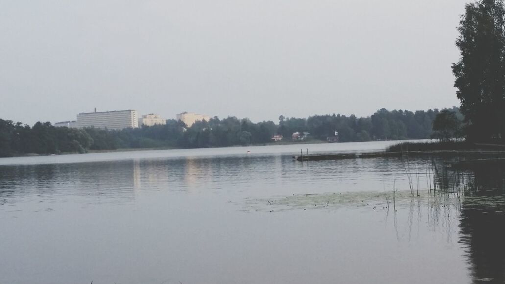 water, lake, clear sky, reflection, waterfront, tree, tranquil scene, tranquility, built structure, copy space, river, architecture, scenics, building exterior, nature, beauty in nature, sky, calm, outdoors, no people