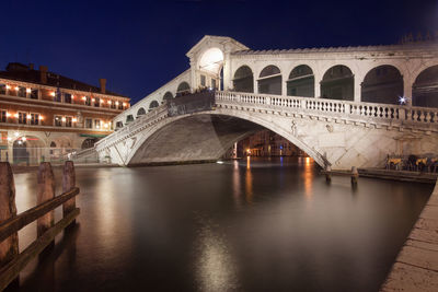 Arch bridge over river at night