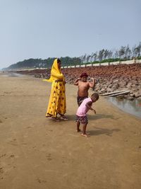 Rear view of women on beach against sky