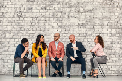 Group of people sitting on brick wall