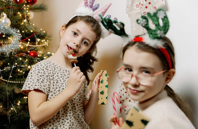 Two girls hold gifts in their hands from a wall advent calendar.